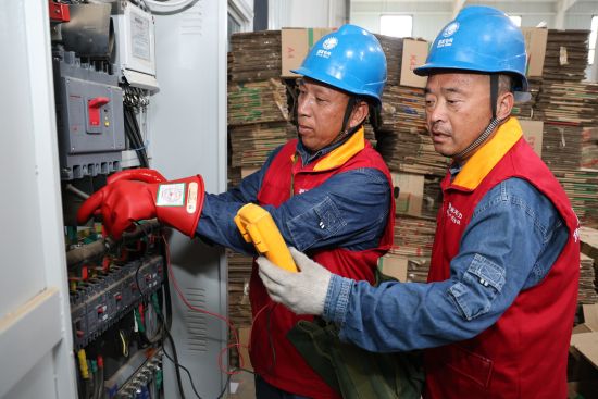 图为国网濮阳公司工作人员帮助企业检测设备